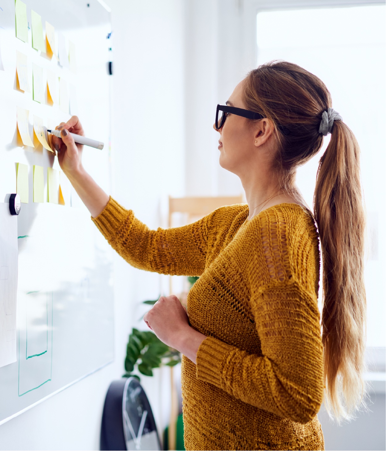 Eine Frau schreibt während einer Brainstorming-Sitzung Notizen auf einem Whiteboard.